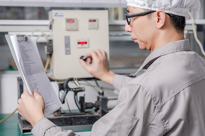 a male worker is reading a document and doing a pull test with a machine